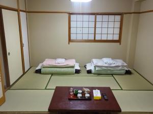 ein Zimmer mit zwei Betten und einem Tisch darin in der Unterkunft Imazato Ryokan - Vacation STAY 02547v in Osaka