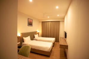 Habitación de hotel con 2 camas y TV en HILUX COURTYARD, en Palakkad