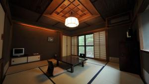 uma sala de estar com uma mesa e uma televisão em Yuzuya Ryokan em Quioto