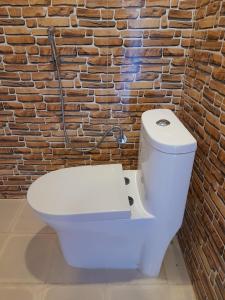 a white toilet in front of a brick wall at The Glasshouse Hotel in Kawasoti +48 photos