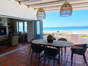 a dining room with a table and chairs and the ocean at C'est la Vie in Paternoster