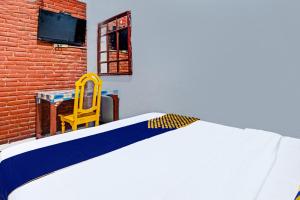 SPOT ON 91915 Homestay Superman في يوغياكارتا: سرير في غرفة مع كرسي اصفر وطاولة