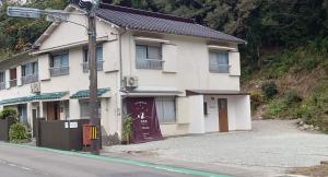 Albany inn Shirahama アルバニーイン白浜 في شيراهاما: مبنى ابيض على جانب شارع