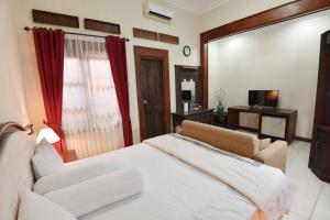 una camera con letto, divano e TV di Ndalem Maharani Guest House a Yogyakarta