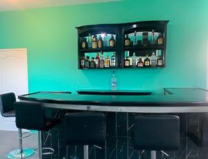 a bar with a green wall and some bottles at Valentine's Castle in Saint Annʼs Bay