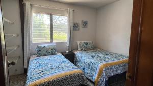 two beds in a room with a window at CASA AZALEA in Guatemala