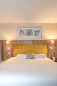 a bedroom with a large white bed with two pictures on the wall at Hotel Residence Loren in Uster