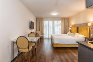 una camera d'albergo con letto, tavolo e sedie di Hotel Residence Loren - contact & contactless check-in a Uster