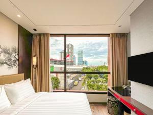 a hotel room with a bed and a large window at Ashley Tang Menteng Jakarta in Jakarta