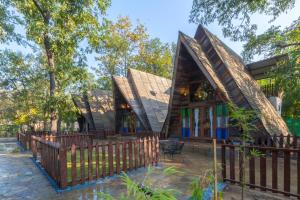 a home with a thatched roof and a wooden fence at Sterling Padam Pench in Khawāsa +80 photos