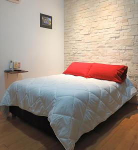 1 cama con almohada roja y pared de ladrillo en Habitaciones amuebladas Veracruz Logos en Veracruz