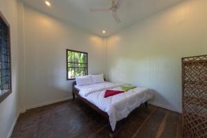 um quarto com uma cama com lençóis brancos e uma janela em The Green Home em Siem Reap