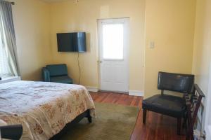 a bedroom with a bed and a chair and a window at Lincoln Manor - Newly Renovated, 1mile from PHL Airport and Sports Stadiums in Prospect Park