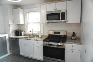 a kitchen with white cabinets and a stove and a microwave at Lincoln Manor - Newly Renovated, 1mile from PHL Airport and Sports Stadiums in Prospect Park
