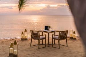 a table and chairs on the beach with the ocean at Regent Phu Quoc in Phu Quoc