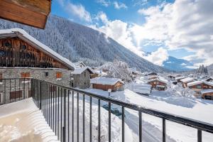 d'un balcon avec des bâtiments enneigés et une montagne. dans l'établissement La Chapelle Aux Pieds Des Pistes, à Chamonix-Mont-Blanc