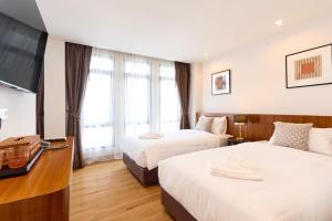 a hotel room with two beds and a flat screen tv at Be Phrasingh Hotel Chiang Mai in Chiang Mai