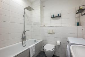 baño blanco con bañera, aseo y lavamanos en Modern Art Apartment, en Leipzig