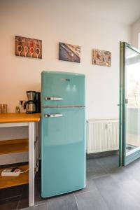 een blauwe koelkast in een keuken naast een tafel bij Arbio I Modern Apart near Leipzig Stötteritz in Leipzig