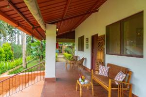 un portico di una casa con panchina e tavolo di StayVista at Firefly By The River with Breakfast a Kushalnagar Altre 37 foto