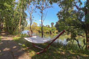 una sedia seduta sul fianco di un fiume di StayVista at Firefly By The River with Breakfast a Kushalnagar