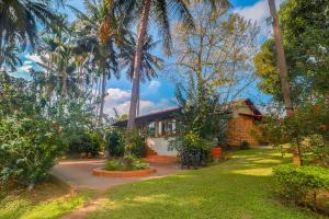 a house with palm trees in front of a yard at StayVista at Firefly By The River with Breakfast in Kushālnagar