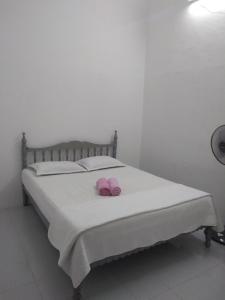 Dos zapatillas rosas sentadas encima de una cama en Rumah Tamu AZ Pasir Tumboh, en Kampong Binjai