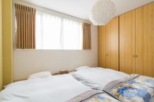 a bedroom with two beds and a large window at Aica TABI-NE in Kanazawa
