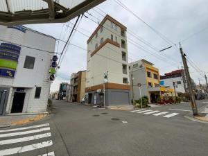 uma rua vazia com um edifício na berma da estrada em オレンジの風 em Imabari