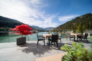 a patio with tables and chairs and a view of a lake at Hotel Seehof in Monguelfo
