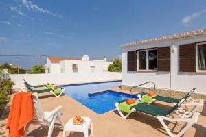 a villa with a swimming pool and two lawn chairs at Villa CLAUDIA Menorca in Cala'n Porter