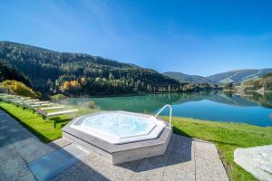 a hot tub sitting on the side of a lake at Hotel Seehof in Monguelfo