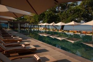 a row of lounge chairs and umbrellas on a beach at Living Asia Resort and Spa in Senggigi