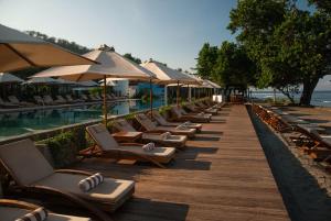 a row of lounge chairs and umbrellas next to a swimming pool at Living Asia Resort and Spa in Senggigi
