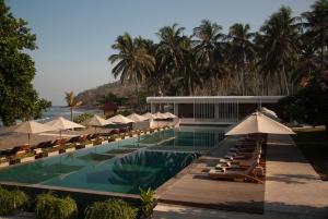 a swimming pool with umbrellas and chairs and a resort at Living Asia Resort and Spa in Senggigi