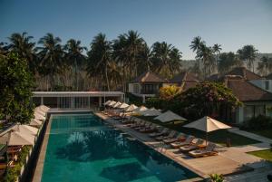 a swimming pool with lounge chairs and umbrellas at Living Asia Resort and Spa in Senggigi