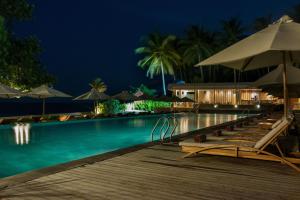 a swimming pool with lounge chairs and umbrellas at night at Living Asia Resort and Spa in Senggigi
