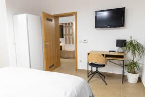 a bedroom with a desk and a tv on the wall at STUDIO APARTMAN BAROSSA in Vinkovci