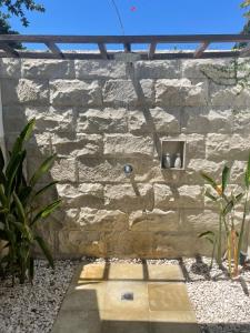 a stone wall with a water fountain in a yard at Wilson's Retreat in Gili Trawangan