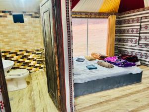 mały pokój z łóżkiem i toaletą w obiekcie Wadi Rum Cave Camp &Jeep Tour w mieście Wadi Rum
