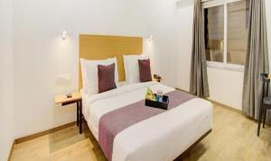 a hotel room with a large white bed and a window at FabHotel Ashray Residency in Navi Mumbai