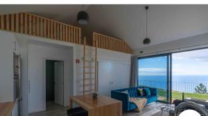 a living room with a loft bed and a blue couch at northsouthviescasinha in Calheta