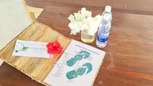 Garden Beach Bungalows Jambiani في جامبياني: طاولة مع كتاب و ورد و زجاجة ماء