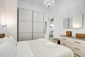 a white bedroom with a large bed and a chandelier at Cosy Apartment- Colosseum- Termini Railway in Rome