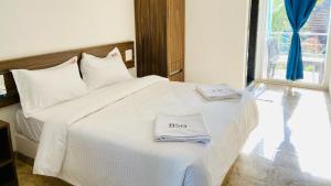 - un lit blanc avec 2 serviettes dans l'établissement BSG Stay - Turtle Beach Morjim Goa, à Morjim