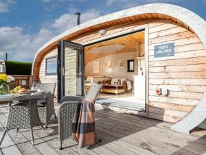 een houten gebouw met een patio met een tafel en stoelen bij Middle Longlands in Cartmel