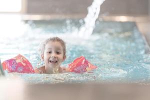 a young child in a swimming pool with a fountain at Gorfion Familotel in Malbun