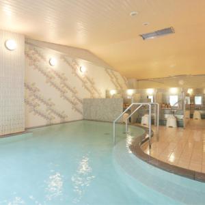 a large swimming pool in a hotel room with a pool at Kyukamura Noto-Chirihama in Hakui