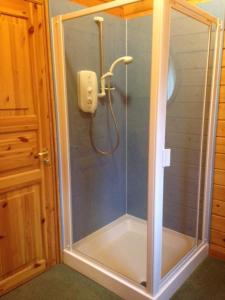 a shower with a glass door in a bathroom at Stable Lodge in Drymen