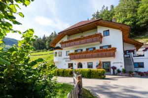 een groot wit huis met een houten dak bij Haidgerberhof - apartments & homemade food in Longostagno